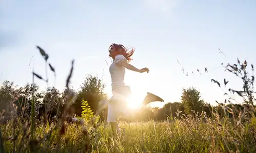 Femme courant dans un champ ensoleillé.